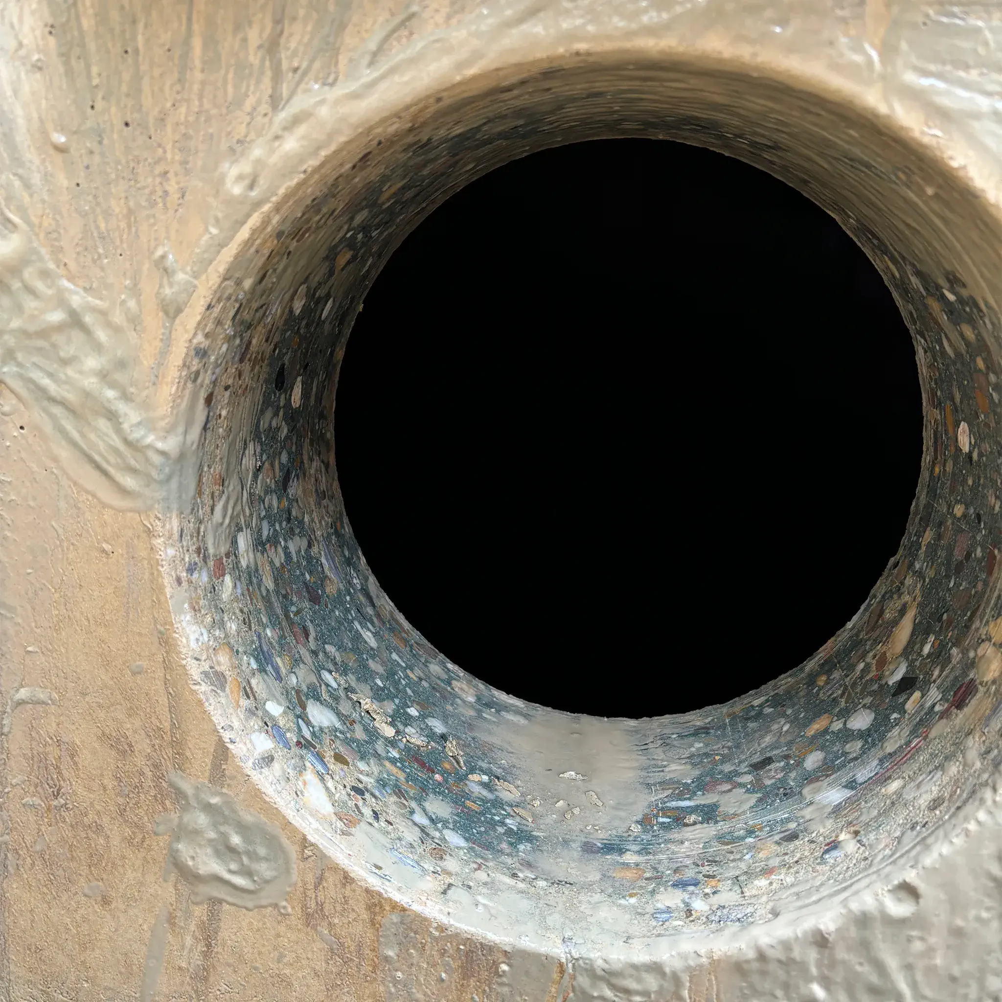 Nahaufnahme einer perfekt kreisrunden und sauberen Kernbohrung in einer dicken Betonwand.